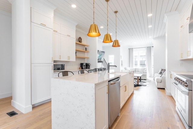 kitchen featuring white cabinets, an island with sink, appliances with stainless steel finishes, and decorative light fixtures