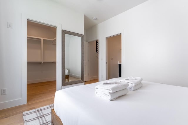 bedroom with light hardwood / wood-style flooring, a walk in closet, and a closet