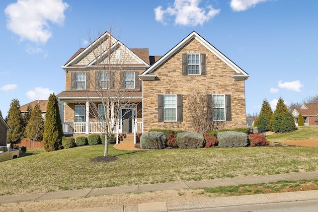 view of front facade with covered porch, a front lawn, and stone siding