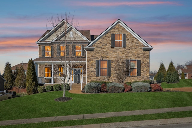 view of front of house with a porch, stone siding, and a front lawn