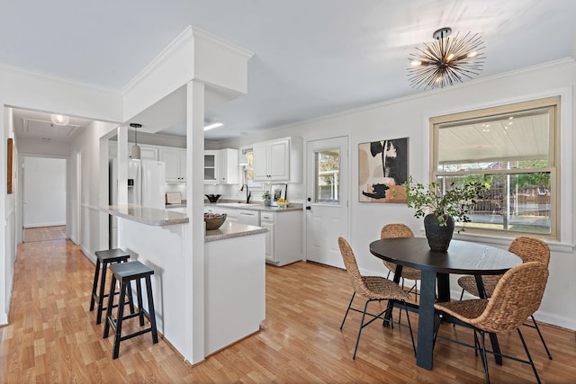 kitchen with hanging light fixtures, white cabinetry, light hardwood / wood-style floors, crown molding, and white fridge with ice dispenser