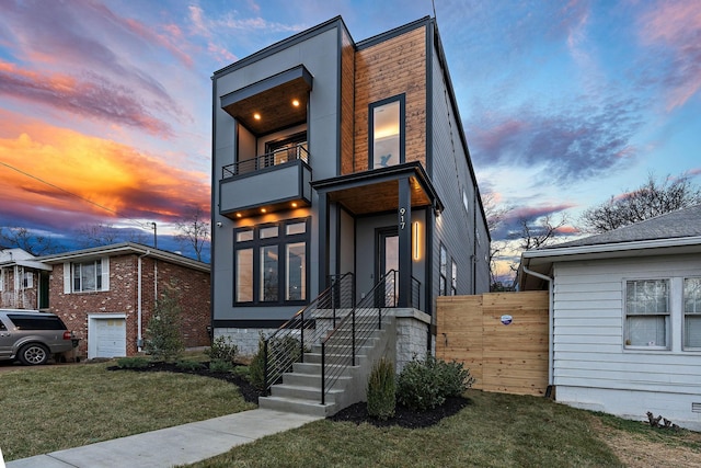 contemporary house featuring a garage, a balcony, and a lawn