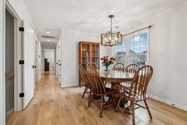 dining area with light wood-type flooring, crown molding, and a notable chandelier