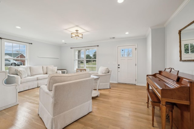 living room with a healthy amount of sunlight, light hardwood / wood-style flooring, and crown molding