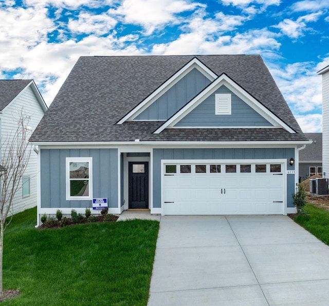 craftsman house with a front yard, central AC unit, and a garage