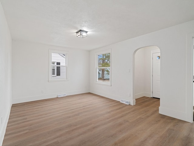 empty room with a textured ceiling and light hardwood / wood-style flooring