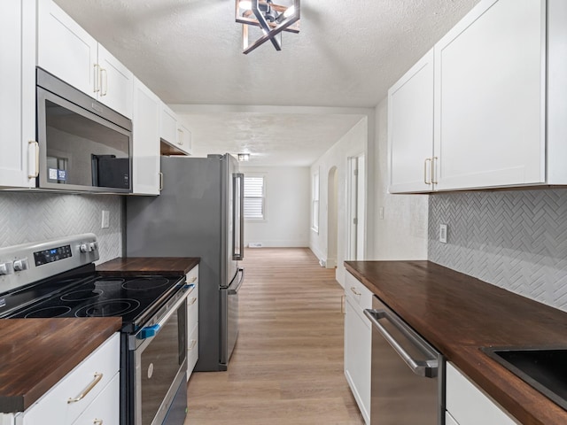 kitchen featuring wooden counters, white cabinetry, and stainless steel appliances