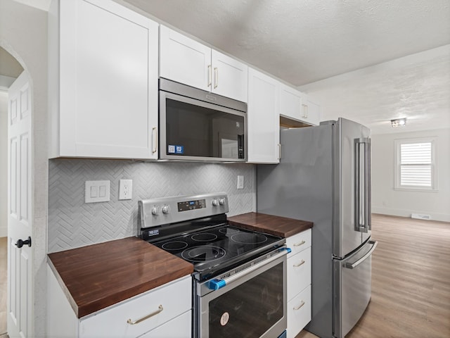 kitchen featuring appliances with stainless steel finishes, wood counters, and white cabinetry