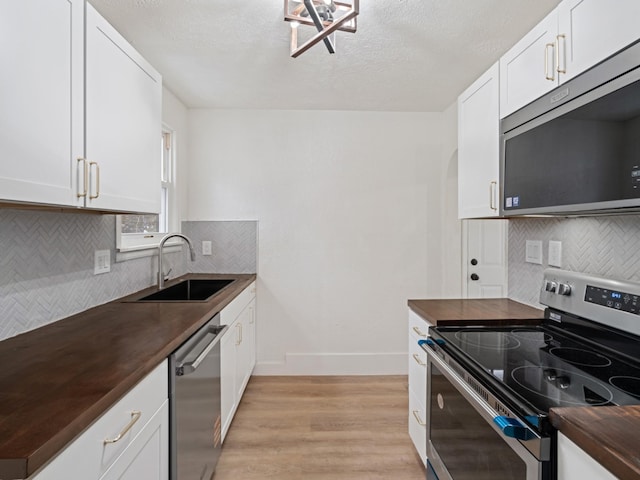 kitchen featuring sink, appliances with stainless steel finishes, white cabinets, and butcher block countertops