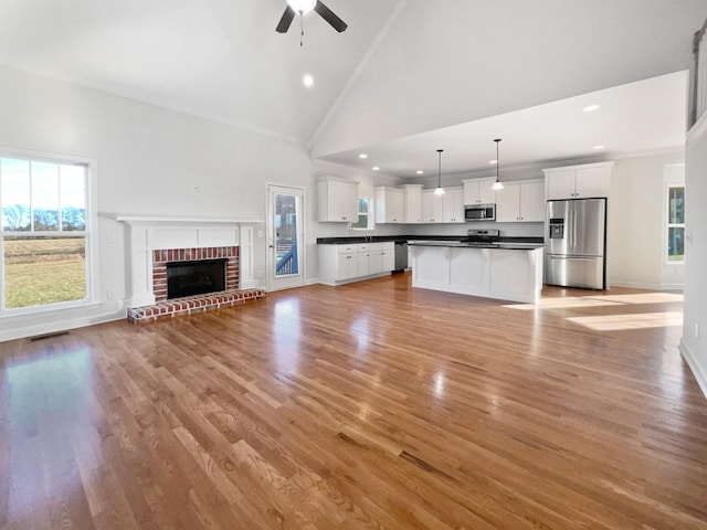 unfurnished living room featuring light hardwood / wood-style floors, high vaulted ceiling, ceiling fan, and ornamental molding