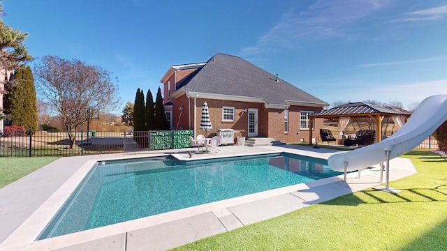 view of swimming pool featuring a lawn, a patio area, area for grilling, a water slide, and a gazebo