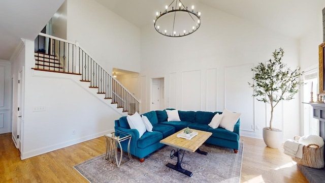 living room featuring light hardwood / wood-style floors, an inviting chandelier, and a towering ceiling