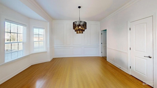 unfurnished dining area with light wood-type flooring, crown molding, and an inviting chandelier