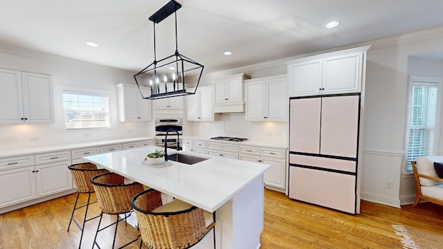 kitchen featuring white cabinetry, fridge, sink, and an island with sink