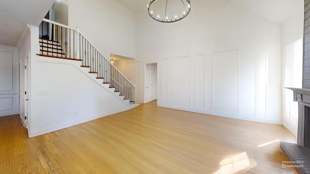 interior space with light wood-type flooring, a towering ceiling, and a chandelier