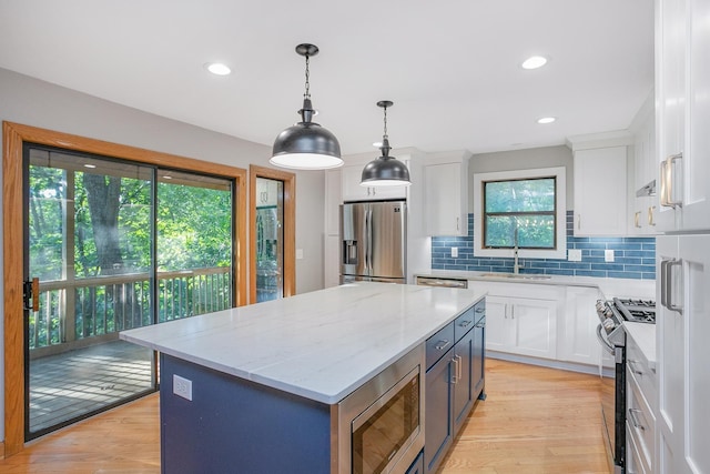 kitchen with sink, white cabinetry, pendant lighting, a kitchen island, and stainless steel appliances