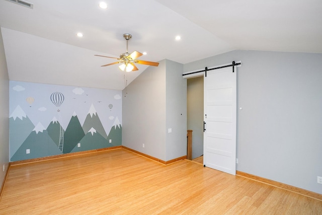 bonus room featuring lofted ceiling, hardwood / wood-style floors, ceiling fan, and a barn door