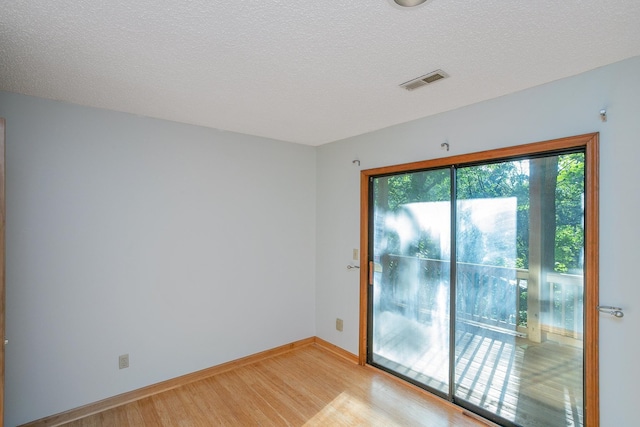 unfurnished room with a textured ceiling and light hardwood / wood-style floors