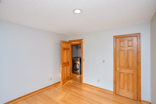 unfurnished bedroom featuring washer / clothes dryer, a textured ceiling, and light wood-type flooring