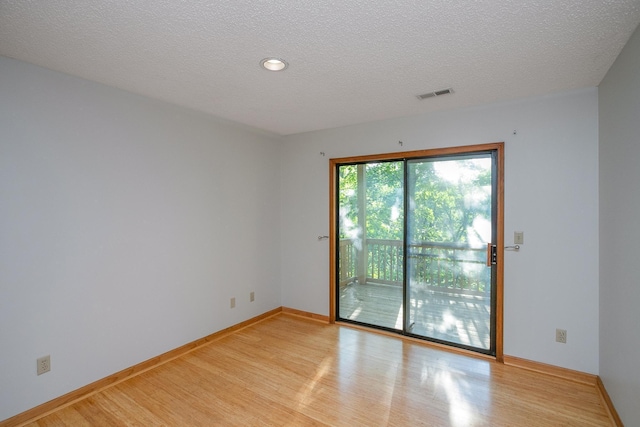 spare room with a textured ceiling and light hardwood / wood-style flooring