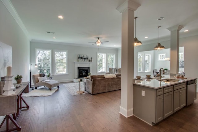 kitchen with sink, crown molding, stainless steel dishwasher, hanging light fixtures, and ornate columns