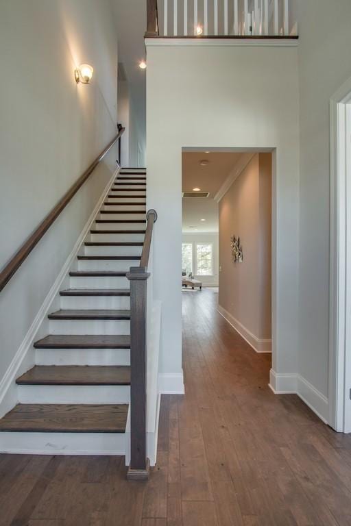 stairs with a high ceiling and wood-type flooring