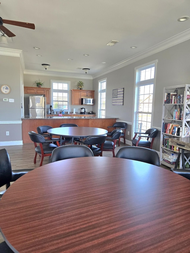 dining room featuring baseboards, visible vents, ornamental molding, and wood finished floors