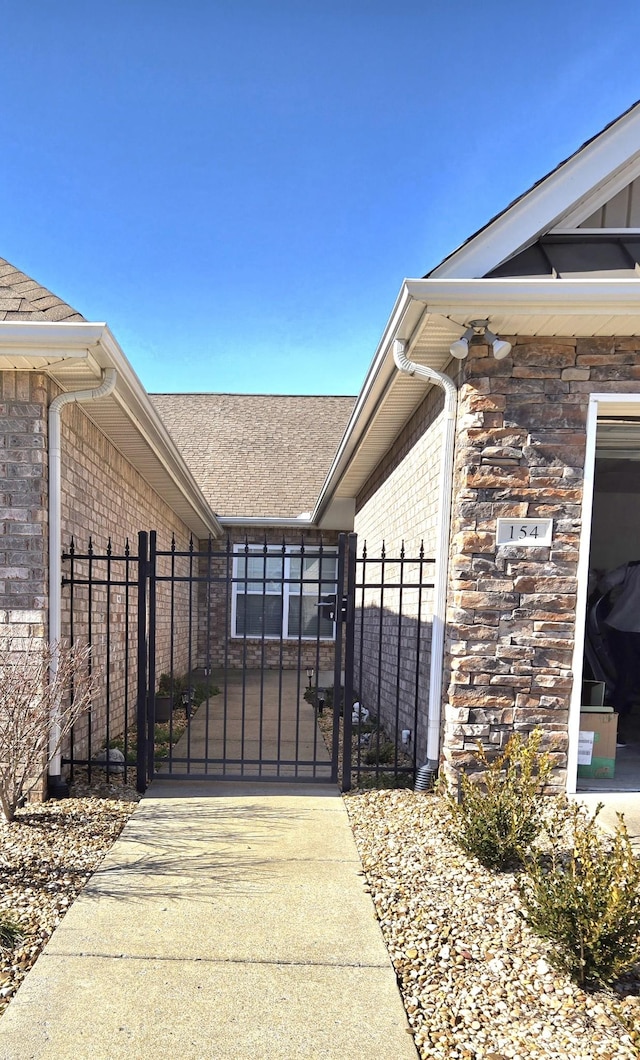 exterior space featuring stone siding, a gate, brick siding, and fence