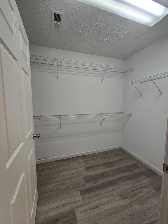 walk in closet with dark wood-type flooring and visible vents