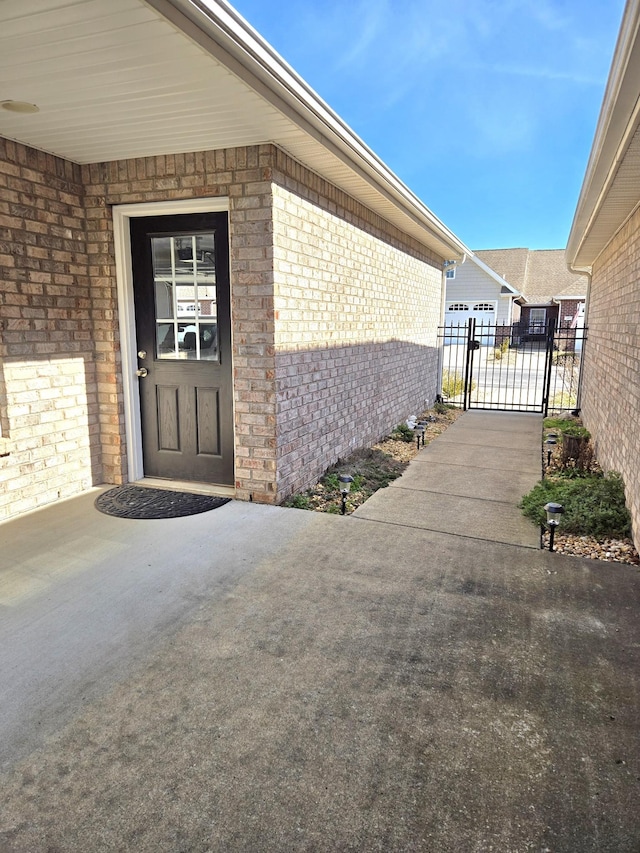 doorway to property featuring a gate, fence, and brick siding