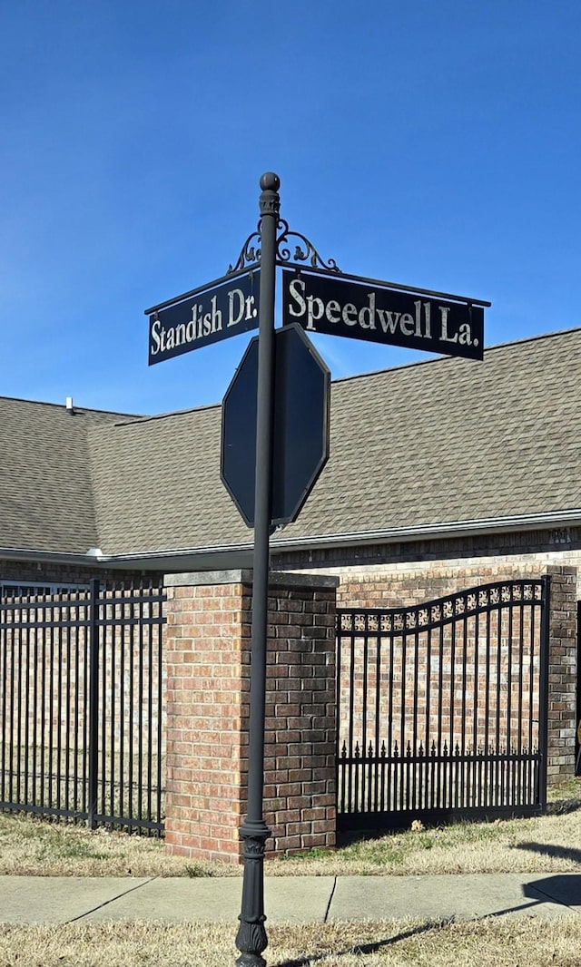 exterior details with fence, brick siding, and roof with shingles