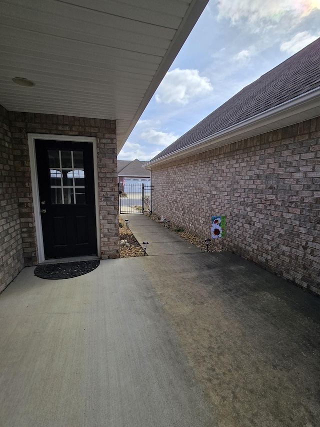 property entrance with fence and roof with shingles