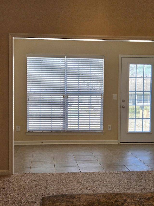 doorway to outside featuring tile patterned flooring and baseboards