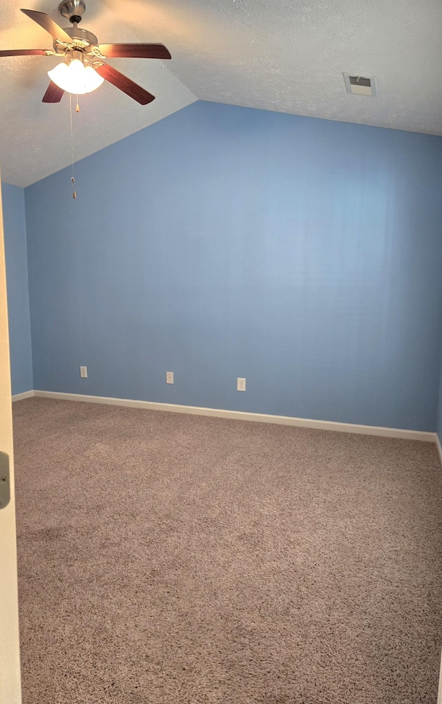 carpeted spare room featuring lofted ceiling, baseboards, visible vents, and a textured ceiling