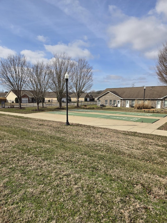 surrounding community featuring shuffleboard, a lawn, fence, and a residential view