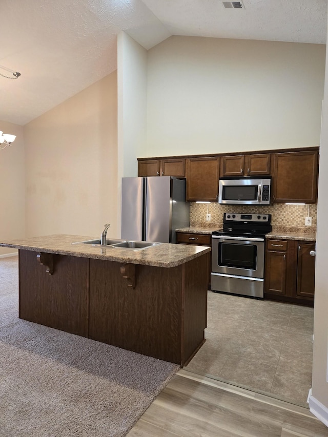 kitchen with an island with sink, a breakfast bar area, stainless steel appliances, and a sink