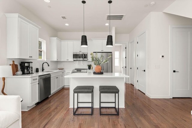 kitchen featuring white cabinets, stainless steel appliances, pendant lighting, and a center island