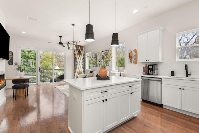 kitchen featuring hanging light fixtures, dishwasher, decorative backsplash, sink, and white cabinetry