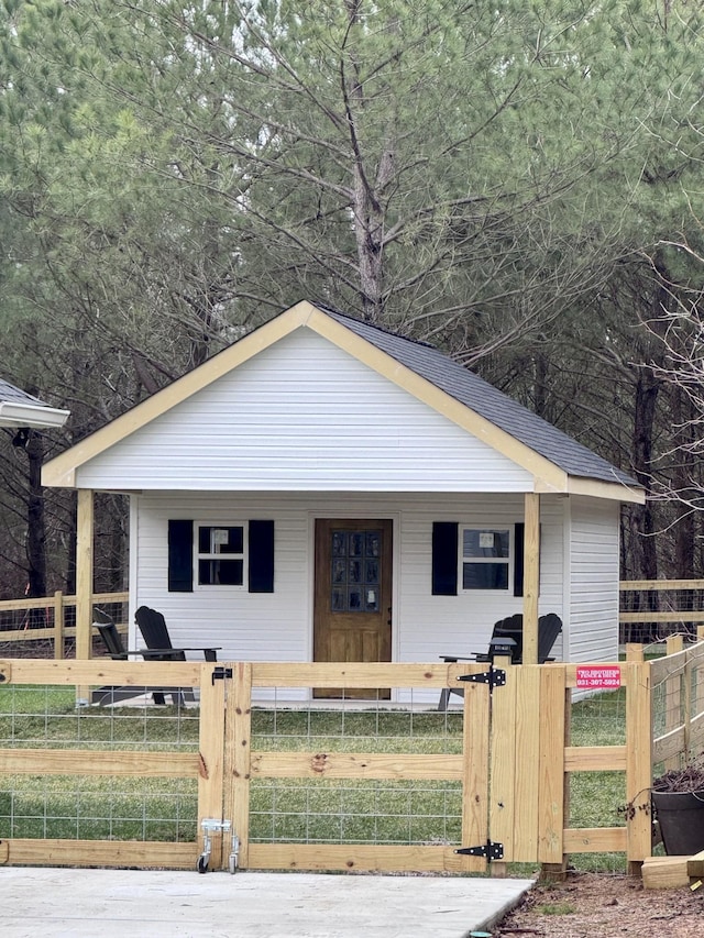 bungalow featuring a fenced front yard and roof with shingles