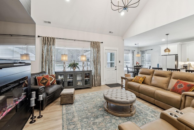 living area with a chandelier, light wood-style flooring, and visible vents