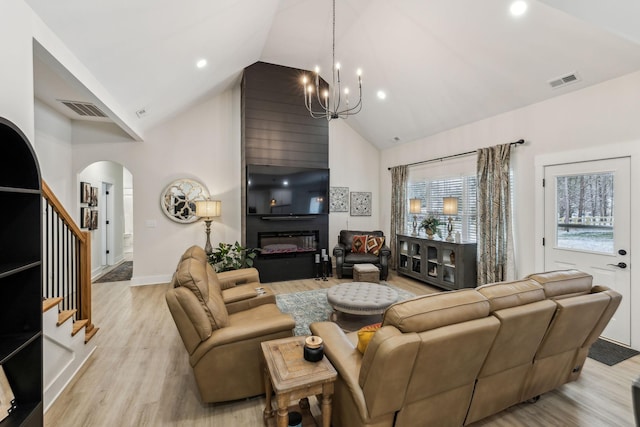 living area featuring light wood-type flooring, high vaulted ceiling, a fireplace, and visible vents