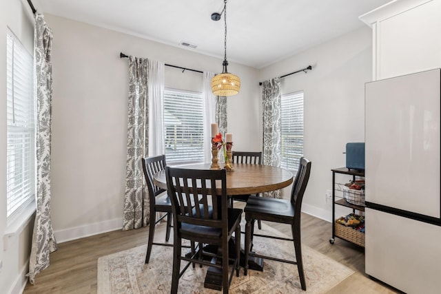 dining room featuring light wood-type flooring, baseboards, and visible vents