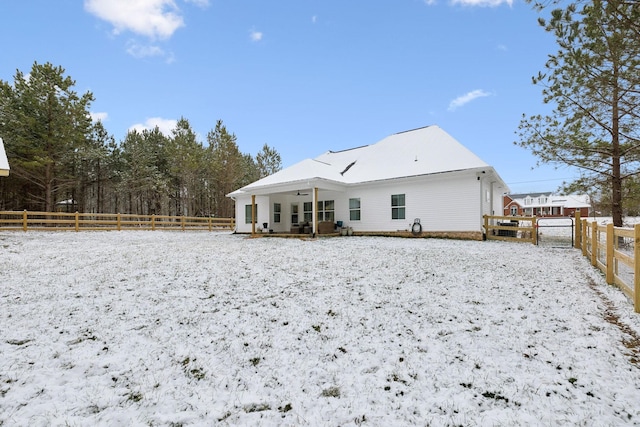 snow covered back of property with a porch and fence