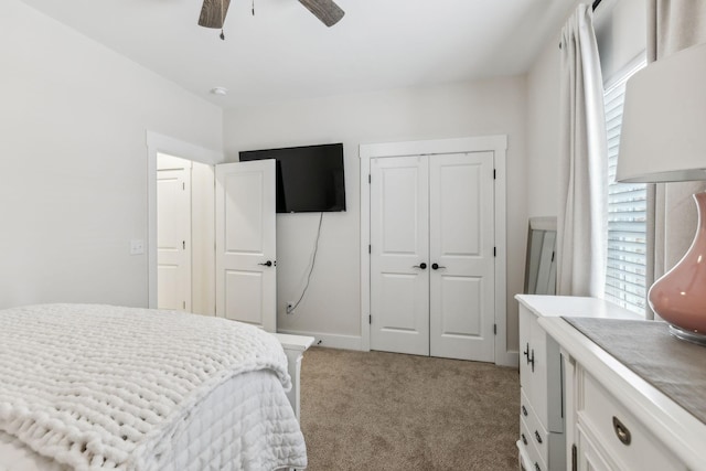 bedroom featuring a ceiling fan, a closet, light carpet, and multiple windows