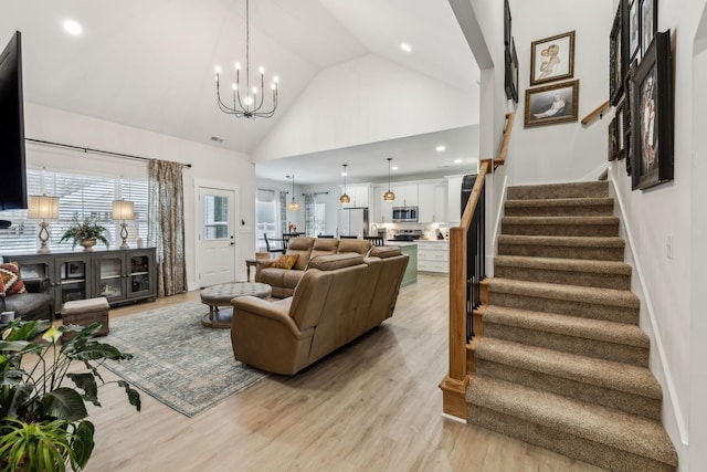 living room featuring stairs, light wood-style floors, high vaulted ceiling, a notable chandelier, and recessed lighting