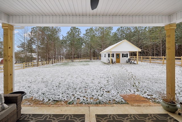 yard covered in snow with an outdoor structure and fence