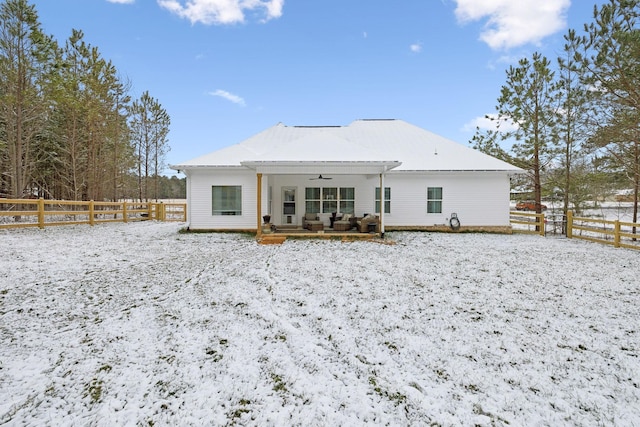 snow covered back of property with fence and a ceiling fan