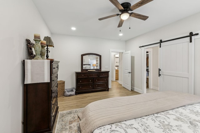 bedroom featuring light wood-style floors, a barn door, a ceiling fan, and recessed lighting