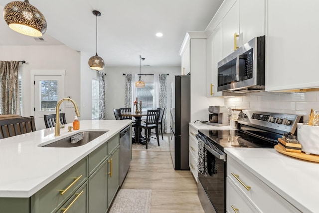 kitchen with a kitchen island with sink, a sink, white cabinetry, appliances with stainless steel finishes, and green cabinetry