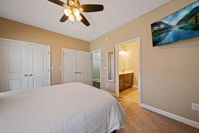 carpeted bedroom with ceiling fan, multiple closets, sink, and connected bathroom